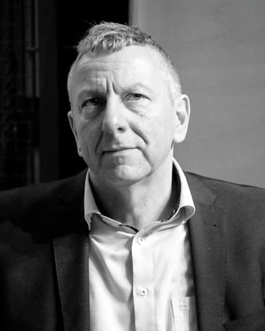 Mann mit kurz geschnittenem Haar trägt Hemd und Sakko in schwarz-weißer Aufnahme