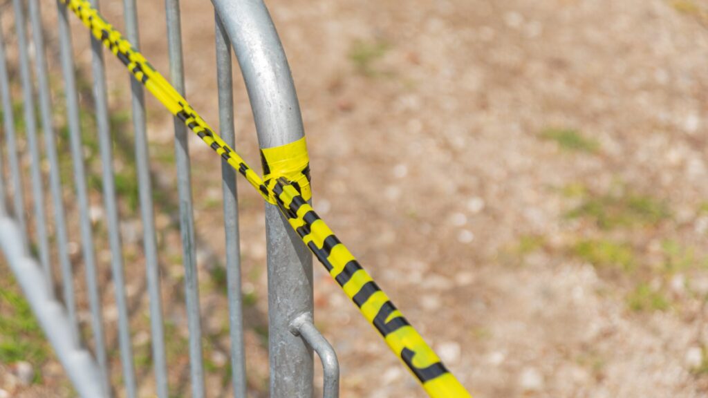 Metallabsperrung mit gelb-schwarzem Sicherheitsband umwickelt